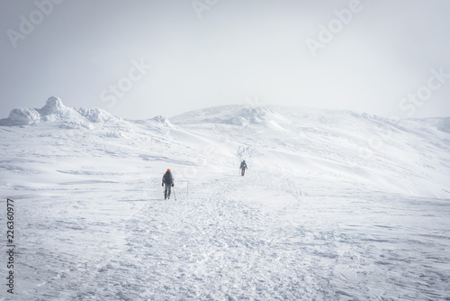 Hiker with backpack climbing on the mountain range. Adventure in the winter wilderness.