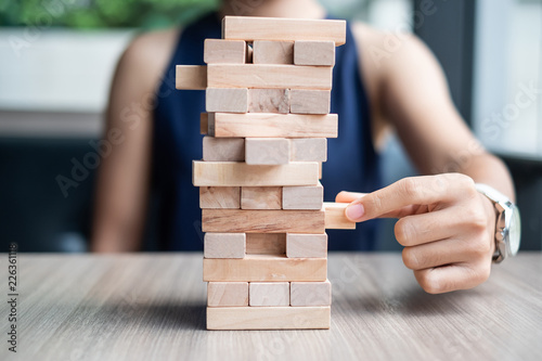 Businesswoman hand placing or pulling wooden block on the tower. Business planning, Risk Management, Solution and strategy Concepts photo