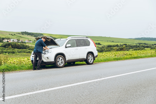man stand near broken car with opened hood. emergency service