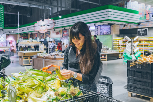 woman choosing corn in grocery shop photo