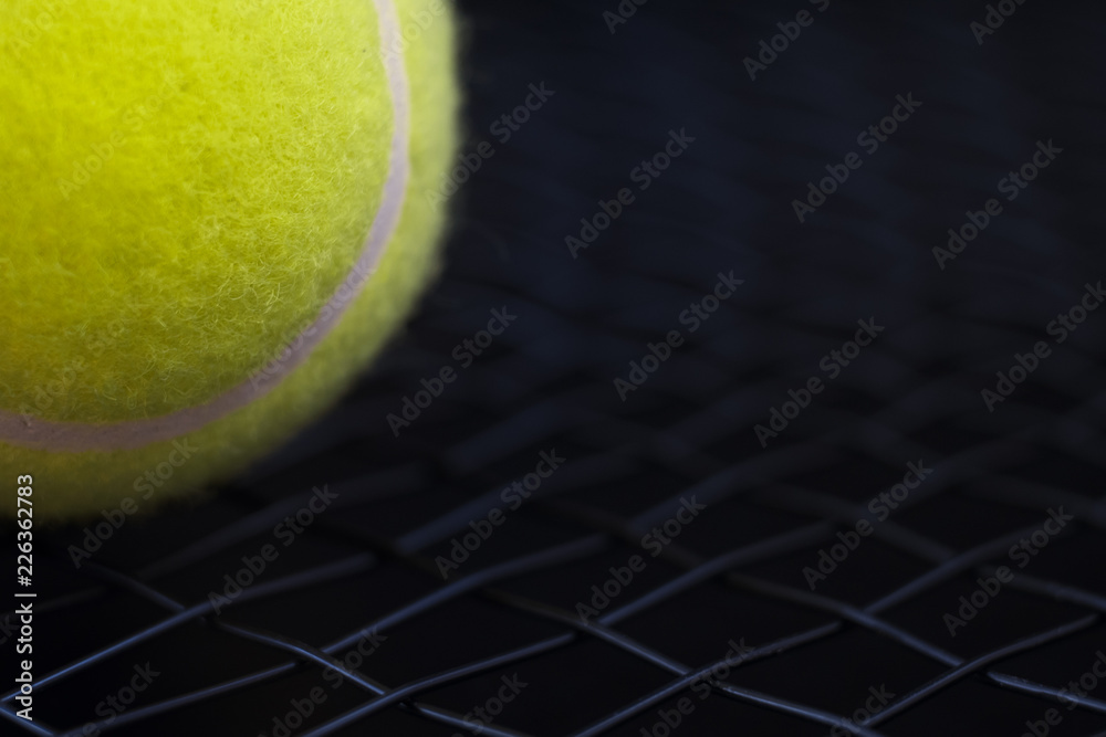 part of new yellow tennis ball on black net racket background, copy space on right