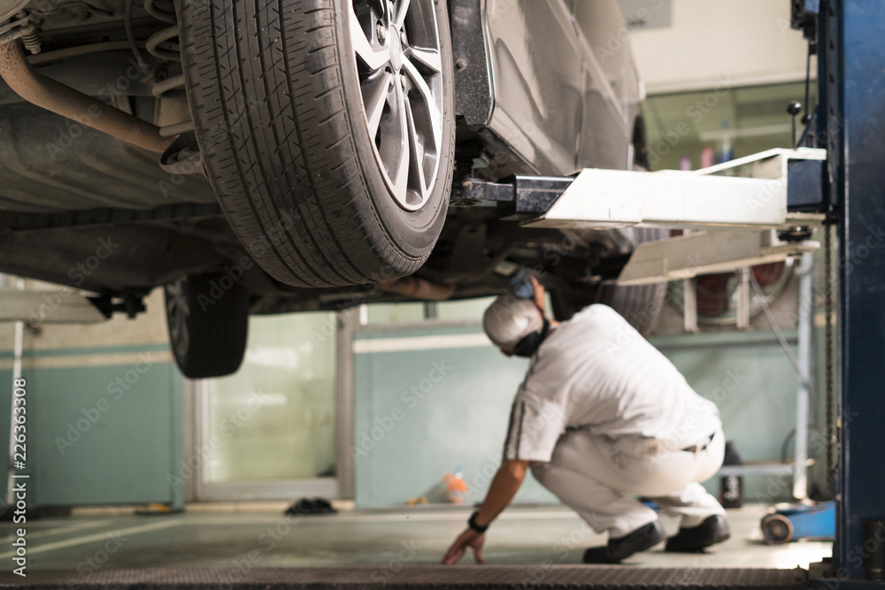 Selective Focus of Technician inspect car suspensions on lifting Selective Focus of Technician inspect car suspensions on lifting