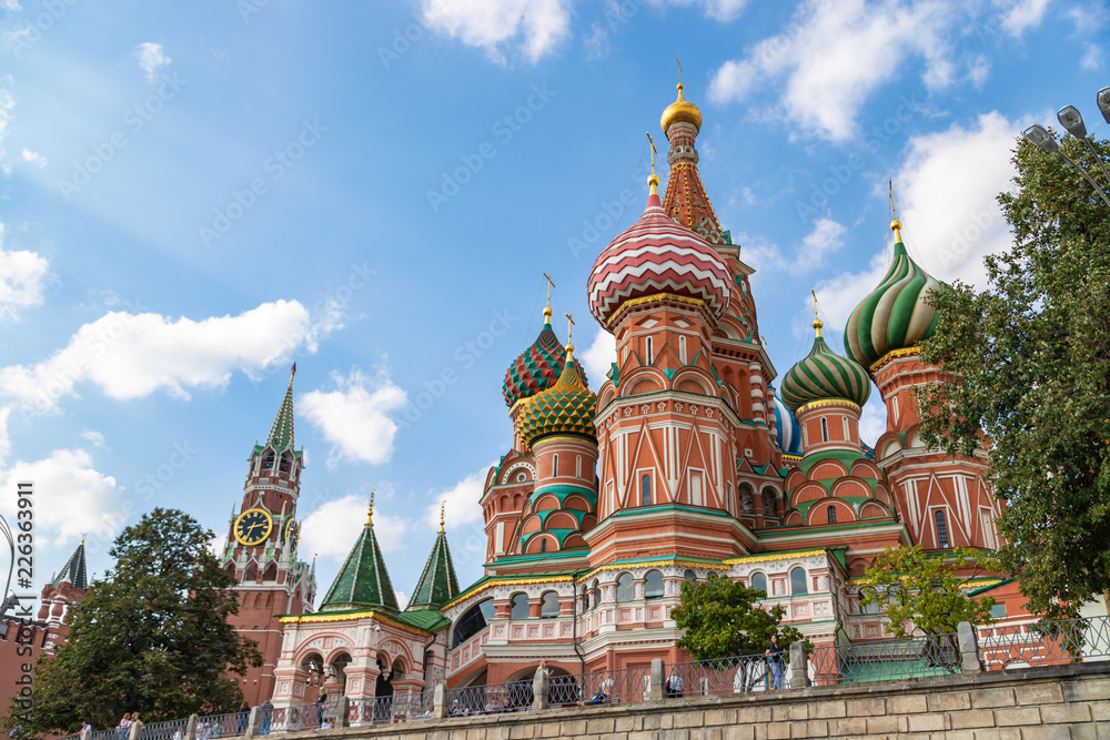 MOSCOW, RUSSIA - SEPTEMBER 22, 2018: Saint Basils cathedral and Spasskaya tower in Moscow. Famous russian landmarks on blue sky background.