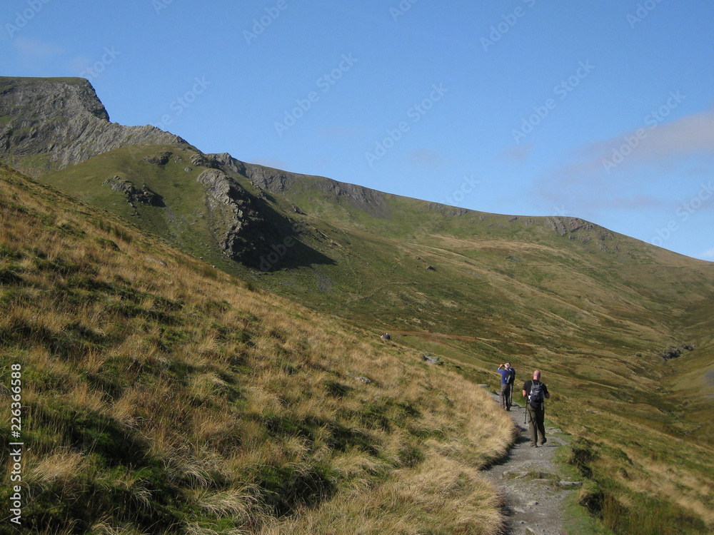 Walkers approaching the challenging scramble of Sharp Edge which leads to the summit of Blencathra, Lake District, England