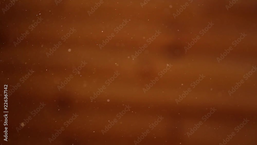 Bokeh brown background. Microscopic blurry shiny particles of home dust flying slowly in air. Real time full hd video footage.