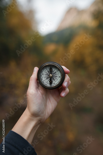 Female hand with a compass on the background of autumn mountains