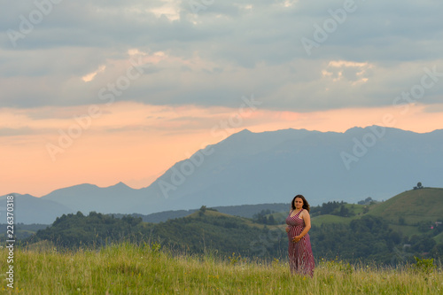 One pregnant woman on sunset landscape