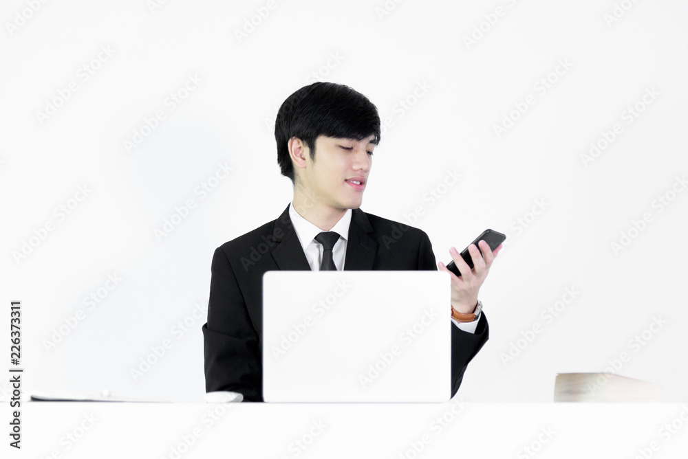 Asian manager businessman sitting at desk and using with phone, isolated on white background. Asian manager businessman sitting at desk and using with phone, isolated on white background.