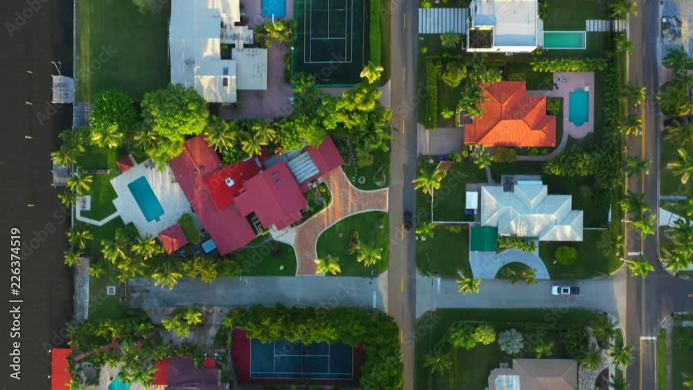 Aerial drone tracking a car driving on a residential neighborhood road