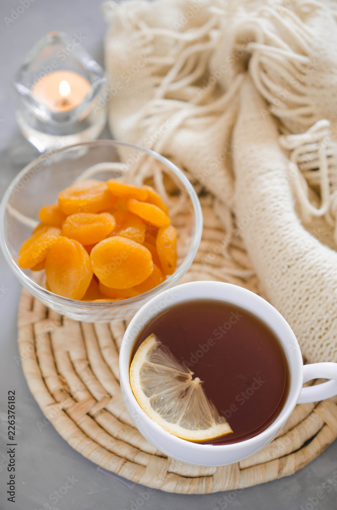 Cup of tea and dried apricots on a table, candles and knited blanket. Cup of tea and dried apricots on a table, candles and knited blanket.