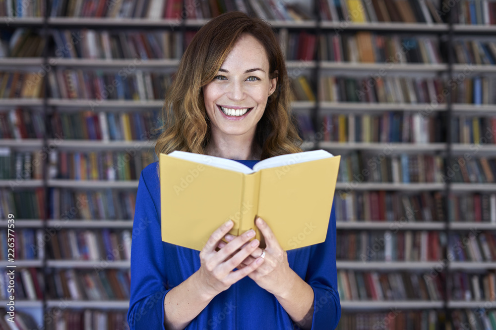 Portrait of woman over 25 in a library reading an opened book, concentrated and smart. Young college student in co-working, concept of studying. Portrait of woman over 25 in a library reading an opened book, concentrated and smart. Young college student in co-working, concept of studying.