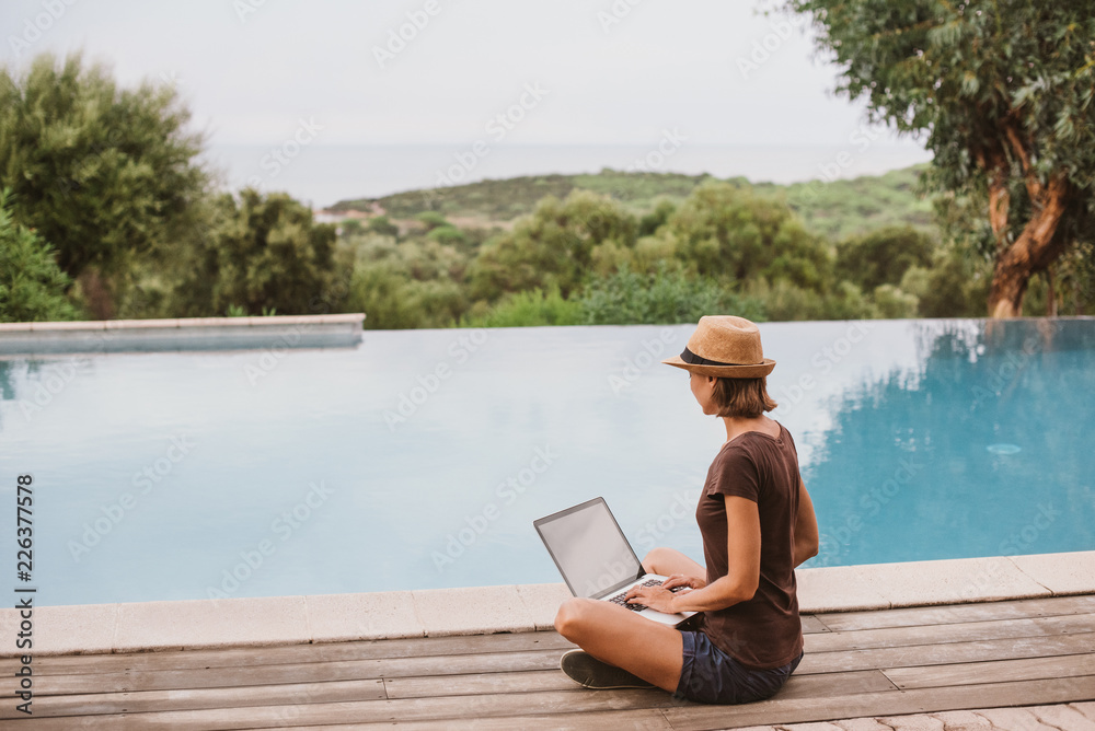 Young woman using laptop computer in hotel. Freelance work and travel concept. People using devices to plan trips, looking for hotels and flights, stay connected to family and office