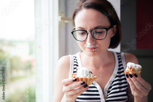 girl eating tasty cakes  sitting by the window  sweet food and pleasure