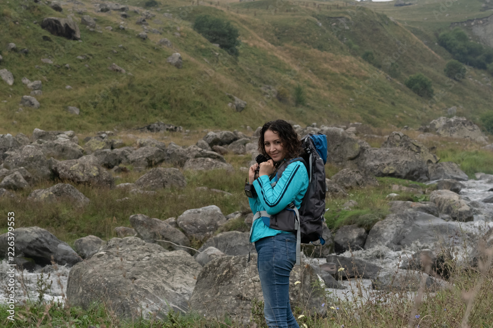 A woman photographs the landscape in the mountains. A woman photographs the landscape in the mountains.