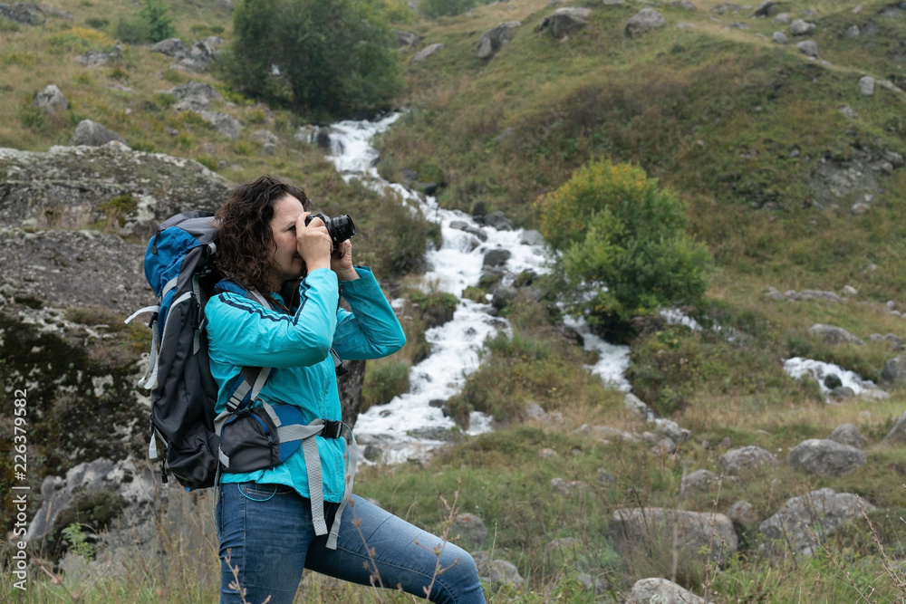 Naklejka premium A woman photographs the landscape in the mountains.