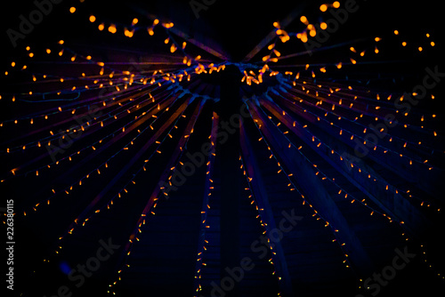 A collection of small little orange lights on the top of a purple ceiling of a tent at a wedding at night in the UK