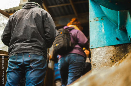 Dangerous looking man behind a woman with a bag in a purple jacket waiting in a queue photo