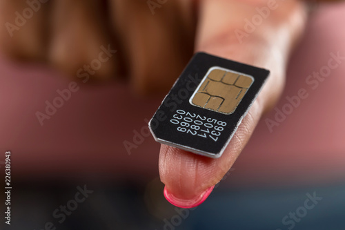 Close - up of the SIM card lying on the girl's finger.