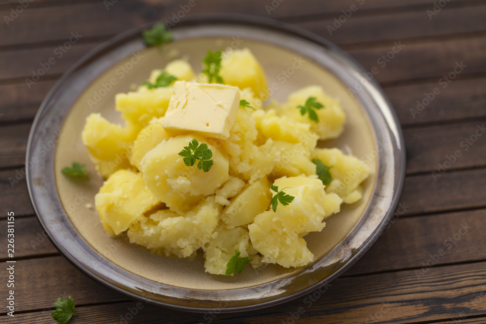 Boiled potatoes with fresh herbs and oil in a bowl on a wooden table Boiled potatoes with fresh herbs and oil in a bowl on a wooden table