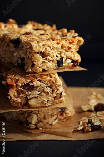 Homemade granola bars with nuts and cranberries over black background