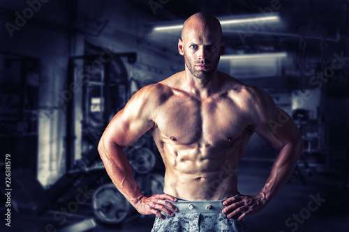 Strong bodybuilder man pumping up muscles after extreme workout . Bodybuilding concept background.