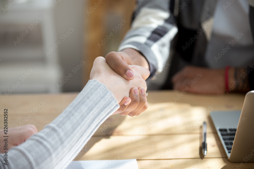 Obraz premium People sitting at the desk in office. Close up handshake two successful business people after good deal, broker and client shaking hands after sales negotiations, greeting, signing contract HR concept