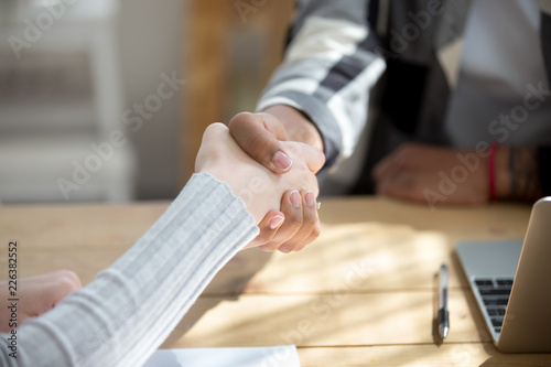 People sitting at the desk in office. Close up handshake two successful business people after good deal, broker and client shaking hands after sales negotiations, greeting, signing contract HR concept