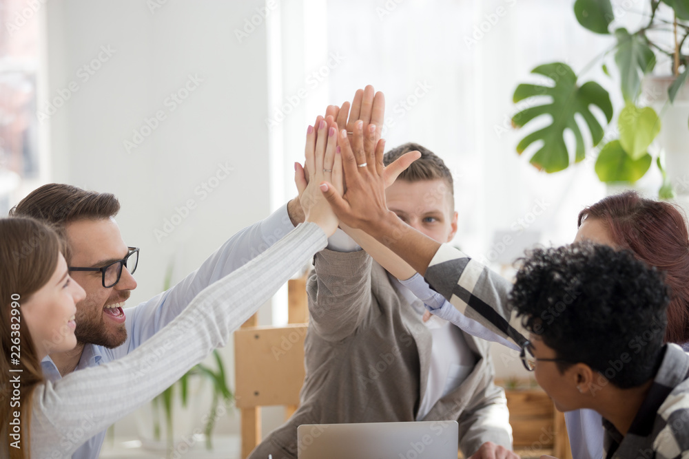 Happy diverse businesspeople team giving high five sitting in office at ...
