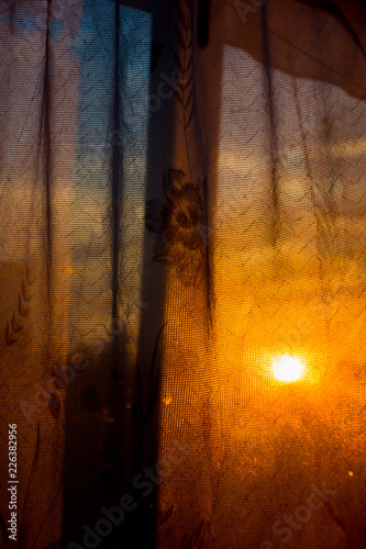 Through the curtain shines the setting sun