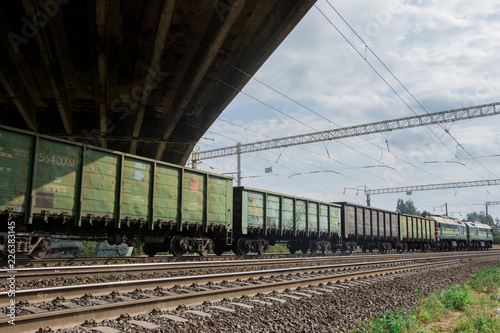 freight train rides by rail under the road bridge