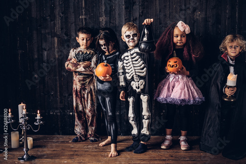 Group of children in costumes during Halloween party in an old house.