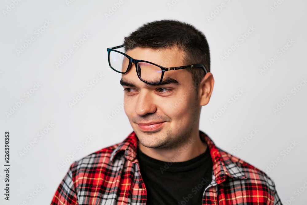 handsome man looks to the side with raised eyeglasses on his forehead on a white background. Close-up handsome man looks to the side with raised eyeglasses on his forehead on a white background. Close-up