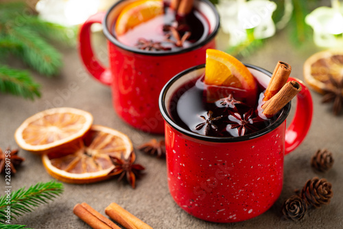 Two cups of christmas mulled wine or gluhwein with spices and orange slices on rustic table top view. Traditional drink on winter holiday photo