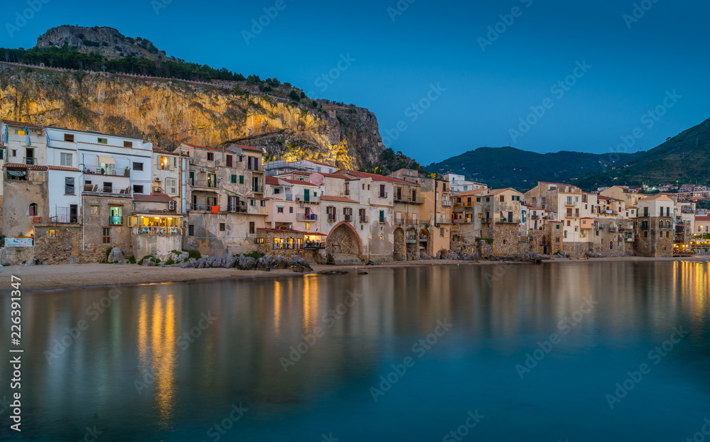 Cefalù waterfront in the evening, with lights reflecting on the water. Sicily, southern Italy.