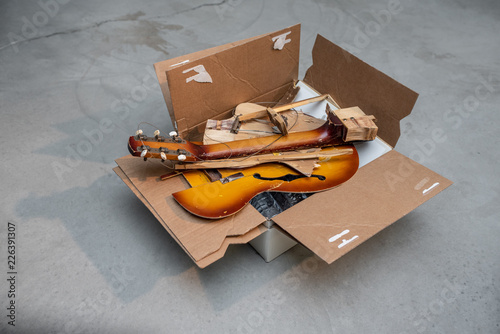 Parts of broken classic guitar in the cardboard box
