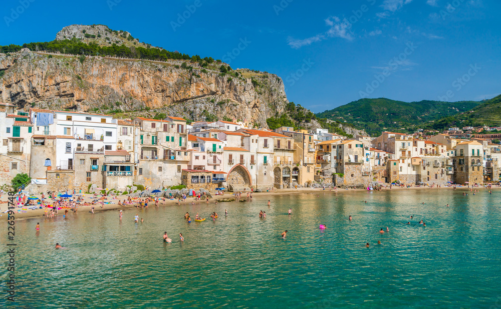 Cefalù waterfront with peole relaxing on a sunny summer day. Sicily, southern Italy.