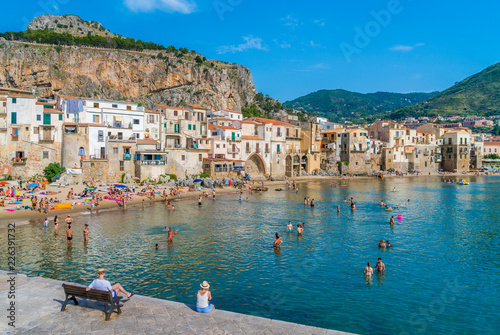 Fototapeta Naklejka Na Ścianę i Meble -  Cefalù waterfront with peole relaxing on a sunny summer day. Sicily, southern Italy.