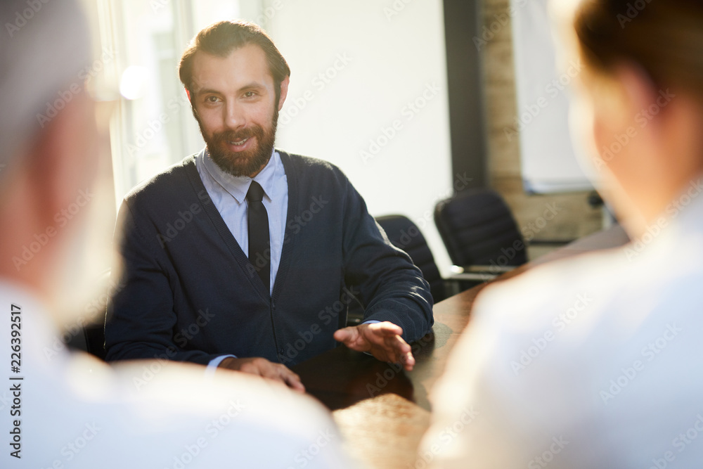Young confident man talking to employers and answering their questions about himself Young confident man talking to employers and answering their questions about himself