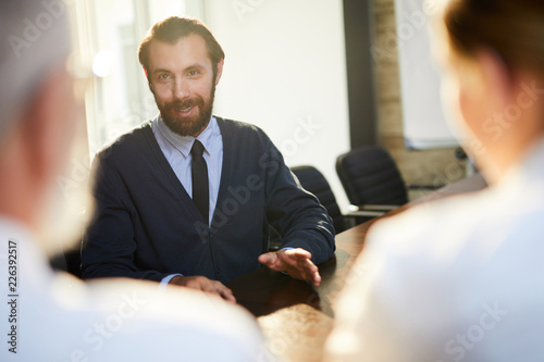 Young confident man talking to employers and answering their questions about himself