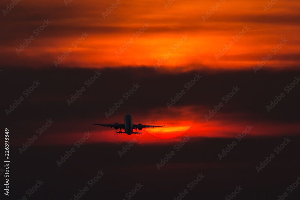 Air plane taking off at sunset near to the sun with beautiful red cloud in background Air plane taking off at sunset near to the sun with beautiful red cloud in background