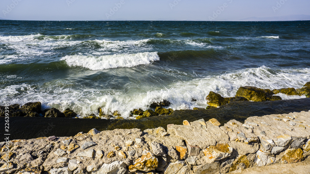 sea with big waves crashing to shore and rocks