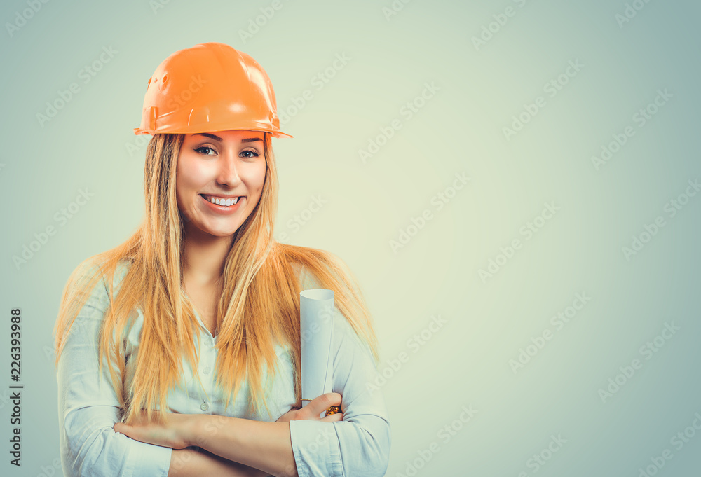 Smiling woman in hardhat holding plans Smiling woman in hardhat holding plans