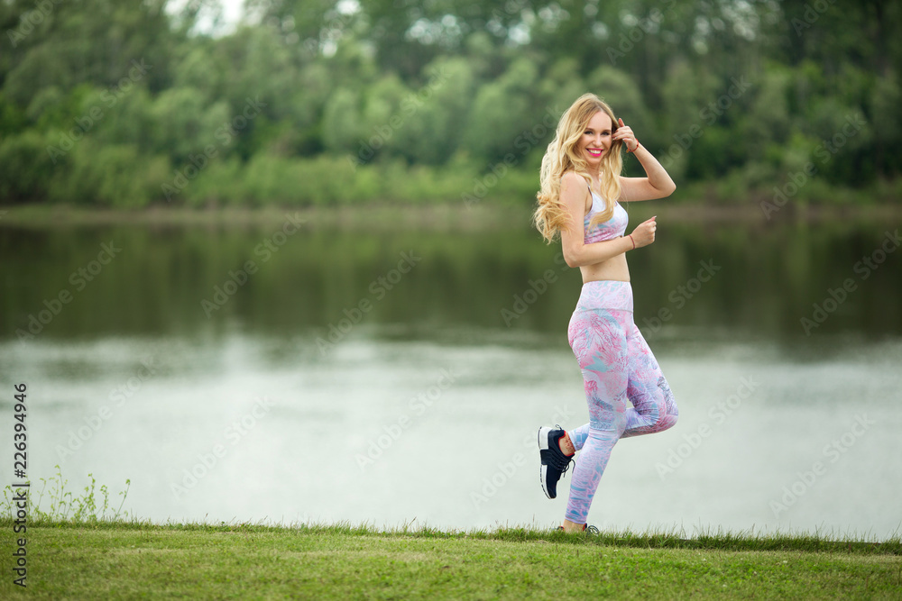 beautiful young girl with flowing hair runs on nature in the summer in a tracksuit beautiful young girl with flowing hair runs on nature in the summer in a tracksuit