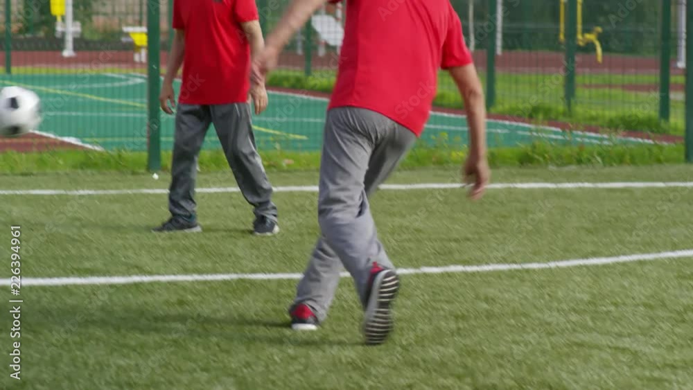 Group of active elderly men having fun together and playing football outdoors on warm summer day Group of active elderly men having fun together and playing football outdoors on warm summer day