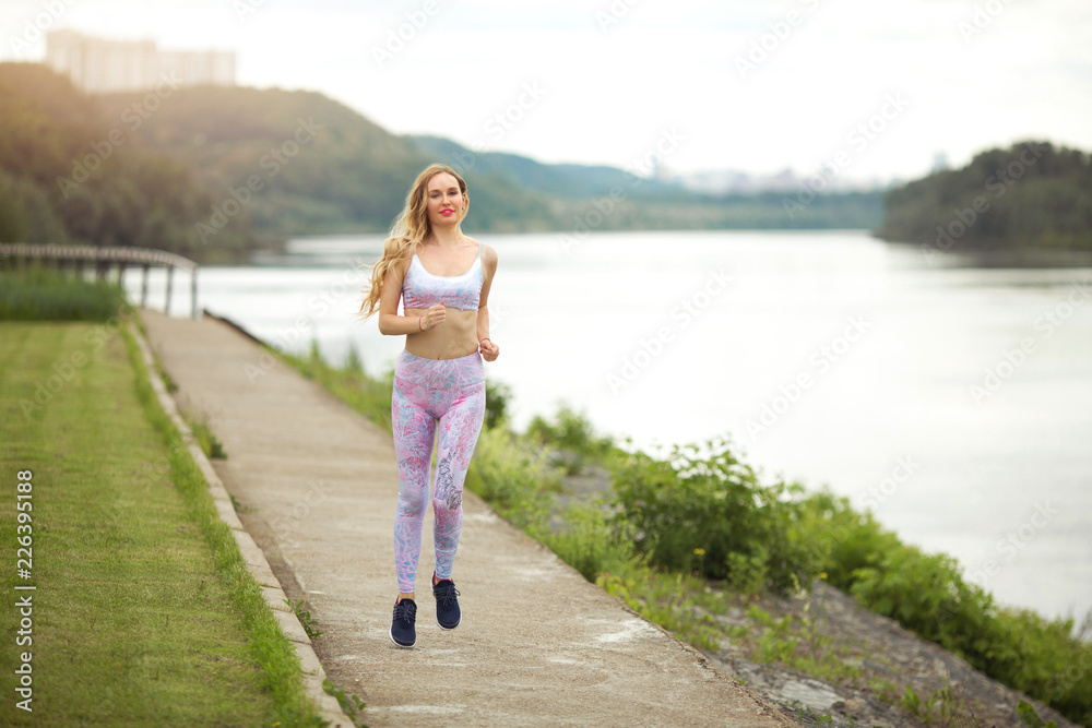beautiful young girl with flowing hair runs on nature in the summer in a tracksuit beautiful young girl with flowing hair runs on nature in the summer in a tracksuit