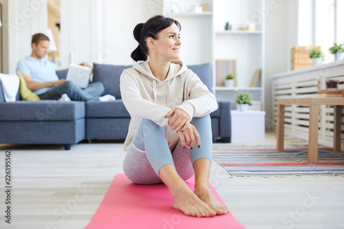 Fototapeta Naklejka Na Ścianę i Meble -  Young healthy active woman sitting on mat and having break in between yoga trainings at home