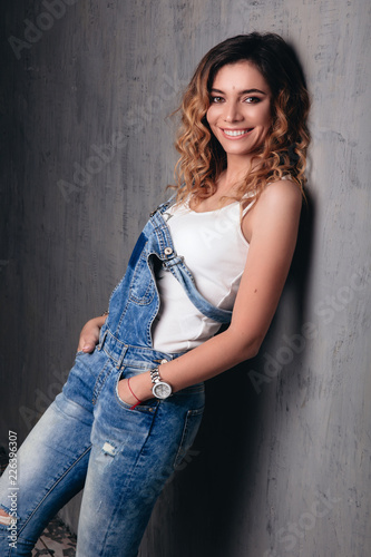 Curly model in a jeans jumpsuit, smiling model
