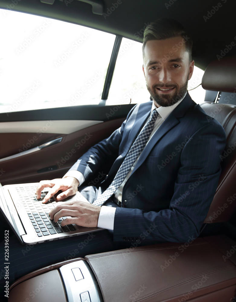 young businesswoman working on her laptop while sitting in the car
