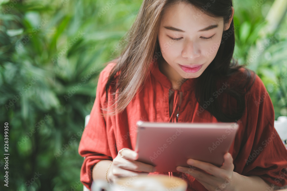Woman holding tablet computer and coffee cup in coffee shop. Woman holding tablet computer and coffee cup in coffee shop.