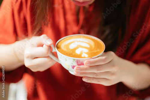 Hand of woman holding a cup of latte art coffee.